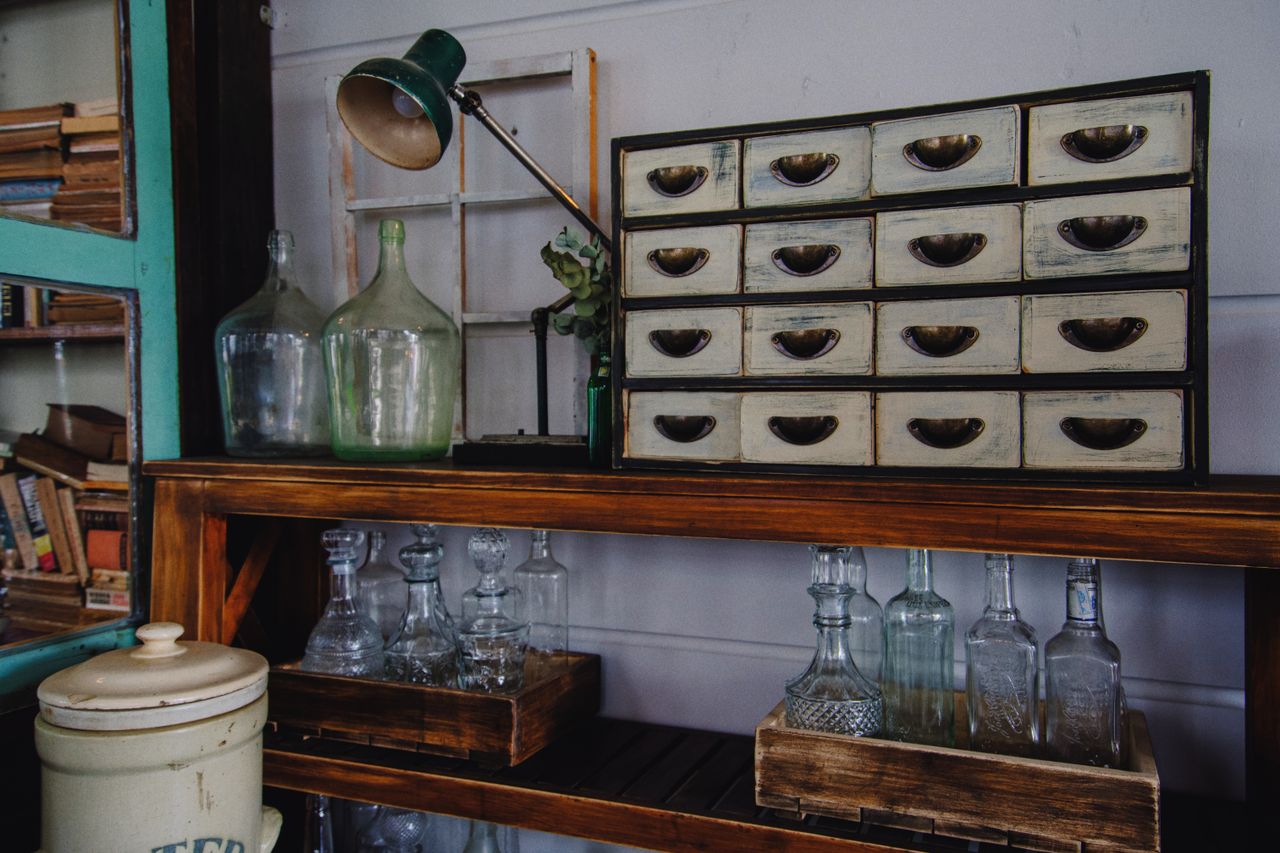 A rustic indoor scene featuring a vintage cabinet and glass bottles on a wooden shelf.